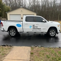 White AP Water Treatment pickup truck used for water quality service in front of a residential garage.