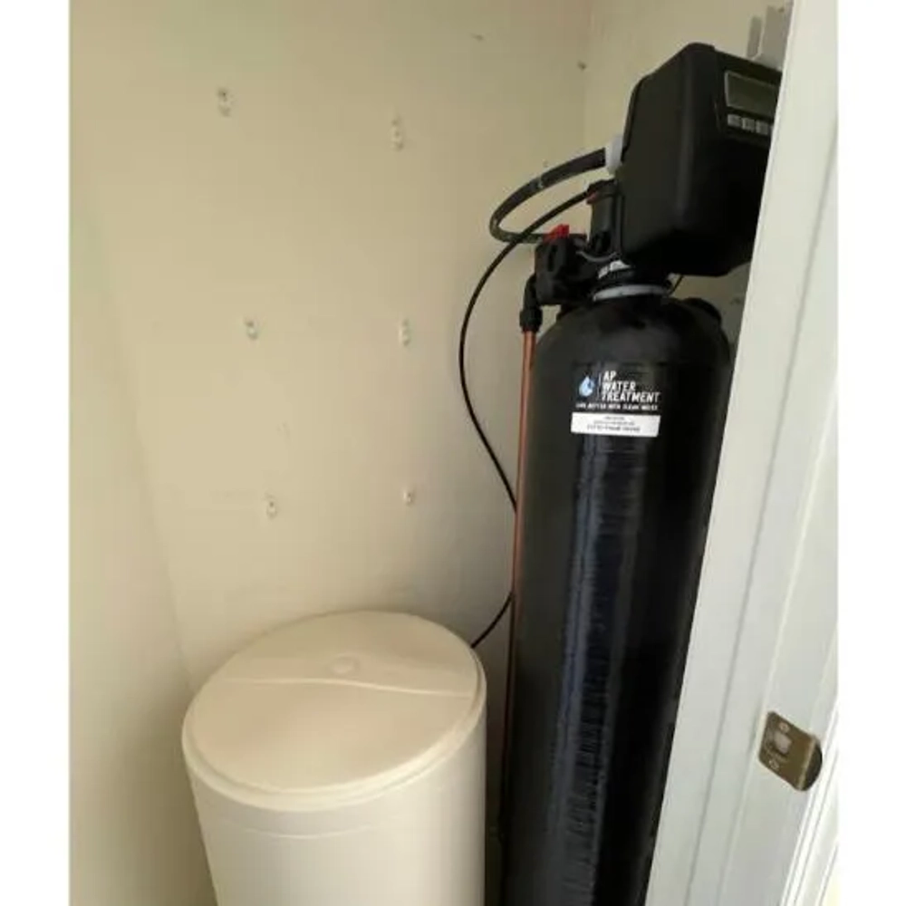 AP Water Treatment single black mineral tank and brine tank installed in a utility closet for softening.