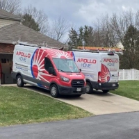 Apollo Home red and white service vans with sunburst logo parked in a suburban setting for home repairs.