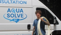 A smiling Aqua Solve NC professional with materials for water filtration services