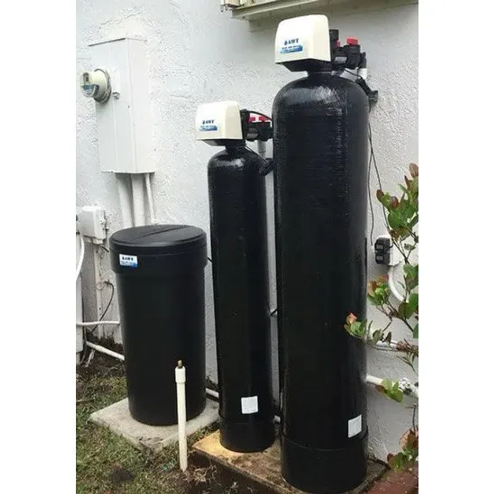 Aqua Water Tech dual-tank water softener installed outdoors in a tropical residential garden