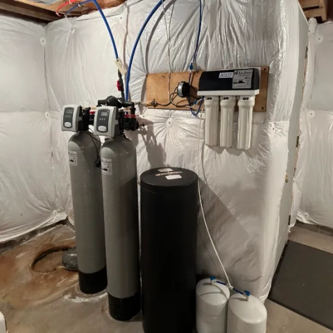 Installed AquaSource water softener system with twin tanks, three pre-filters, and storage tanks.