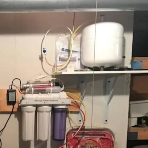 Under-sink or utility-area installed reverse osmosis system, including filter cartridges and pressure tank for water treatment.