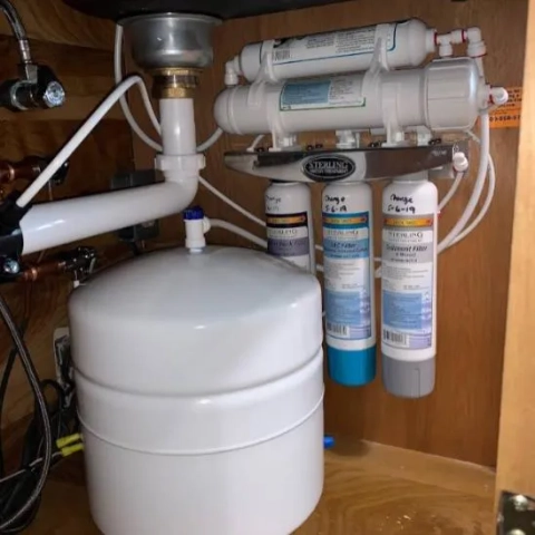 Under-sink reverse osmosis system with Sterling filters, RO storage tank, and plumbing installed.