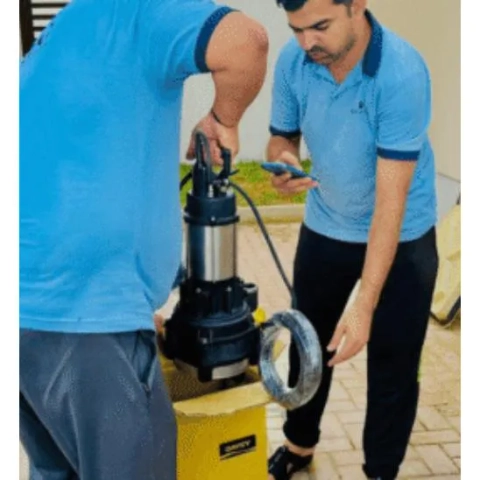 C and C Home Maintenance technicians unboxing a stainless steel submersible pump for installation.