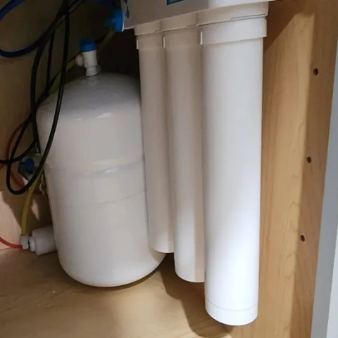 Professional point-of-use residential RO drinking water system with long-reach vertical purification cartridges neatly mounted under a kitchen counter by ClearWave Water Solutions