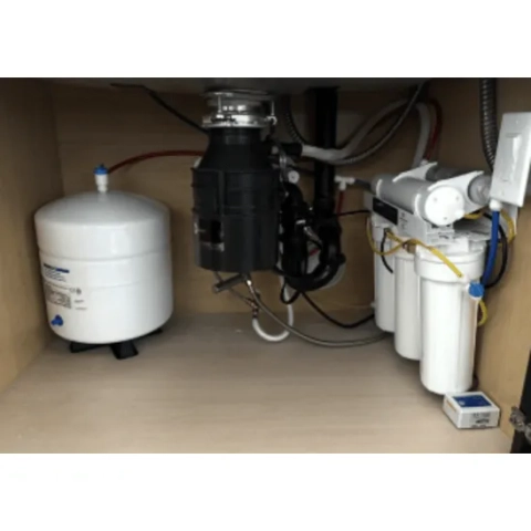 Technical point-of-use kitchen water purification layout featuring color-coded flexible water lines, a shut-off valve manifold, and an electronic leak detector, serviced by Crystal Water Plumbing