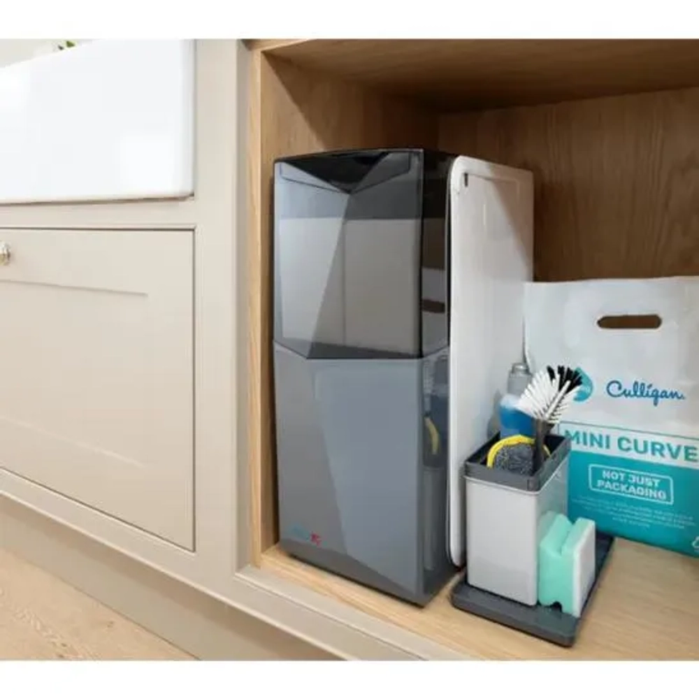 Culligan Arc compact water softener installed neatly inside a wooden kitchen under-sink cabinet