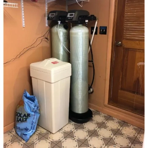 Residential twin-tank water softener system installed by Eastern Water Conditioning, with Solar Salt nearby.