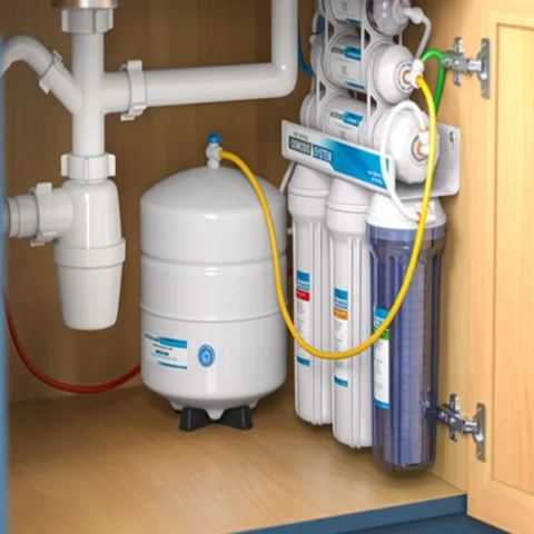 Technical point-of-use kitchen water purification layout featuring a high-capacity reverse osmosis holding tank and flexible lines resting on a pattern-lined utility cabinet base, serviced by Evergreen Waterworks LLC