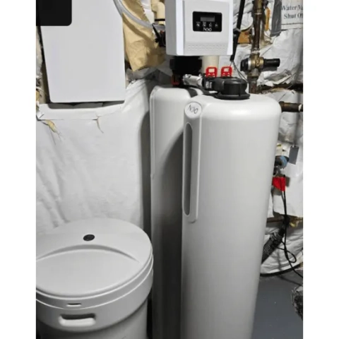F.H. Furr Plumbing water softener.png detailing a space-saving water softening layout featuring two vertical Novo mineral tanks side-by-side, equipped with integrated top-mounted bypass plumbing connections and red-accented release tabs