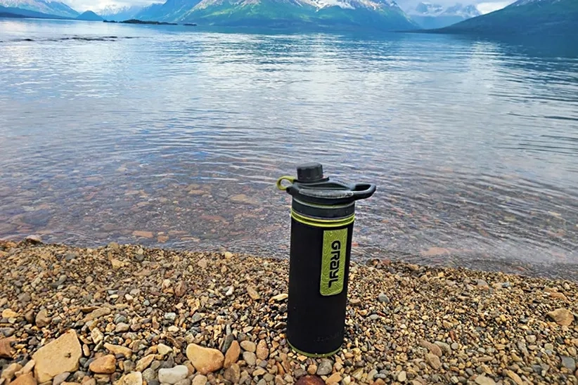  GeoPress Filter Water Bottle with background of lake, which shows it is functional to remove impurities from lake water.