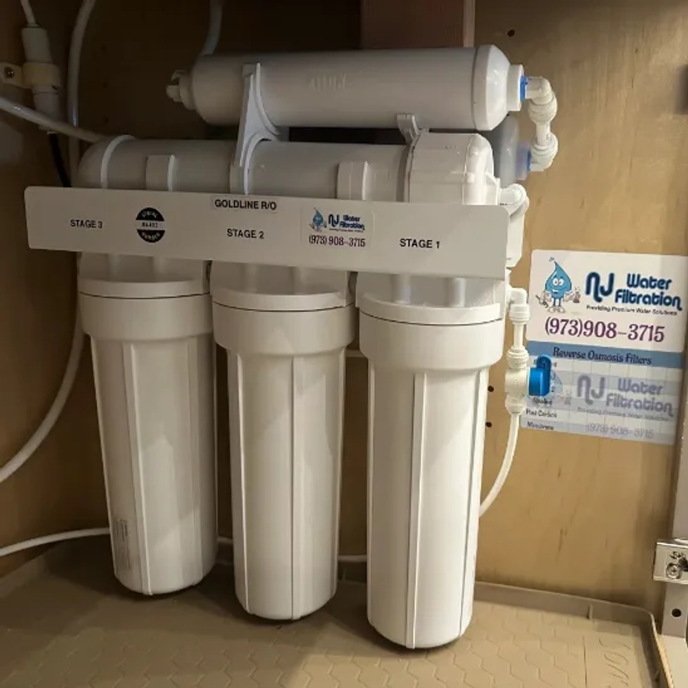 Close-up of a Goldline 4-stage reverse osmosis water filter system installed under a sink.