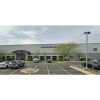 Exterior view of a Grundfos corporate building and office complex with a large parking lot.