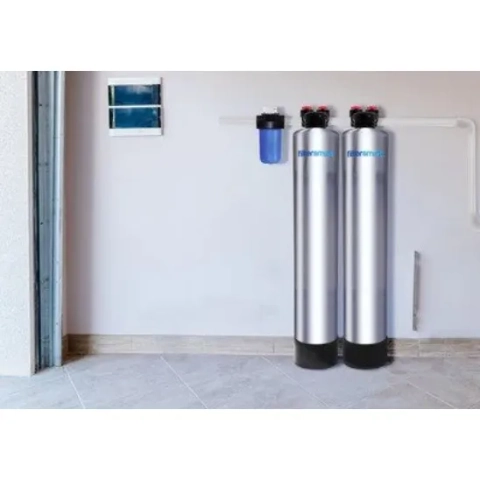 Hf Series Water Softener system, two silver tanks and blue pre-filter, installed in a utility room.