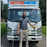 Hotter Water Plumbing technician standing in front of the company service truck in Atlanta, GA.