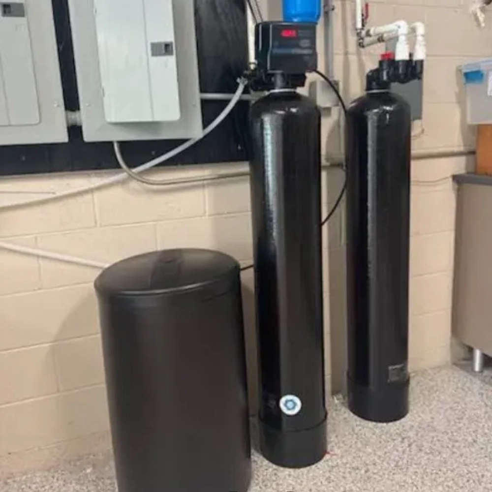 Black HydroLux Signature Series water treatment system, tanks, and control valve in a basement setting.