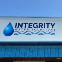 Integrity Water Solutions logo and sign with large blue water drop icon and wavy blue lines underneath.