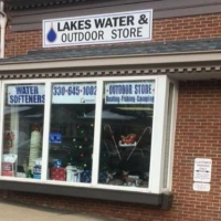Window view of Lakes Water & Outdoor Store, advertising water softeners, fishing, boating, and camping gear.