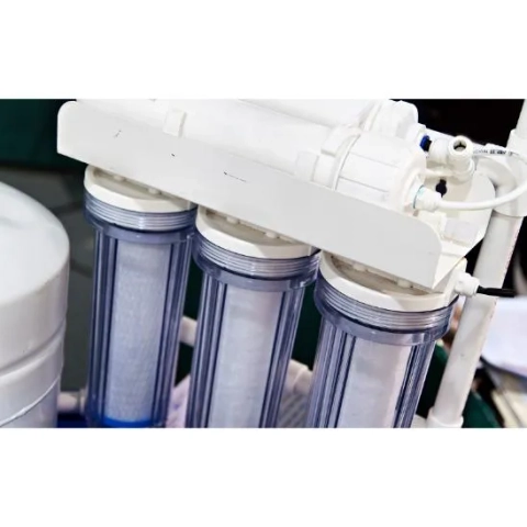 White bracket holding three clear housing water filters showing white sediment cartridges inside.