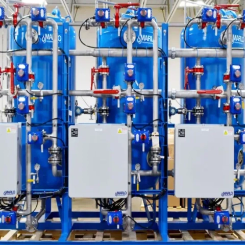 Large-scale commercial water conditioning skid featuring a multi-tank configuration and centralized electronic control hubs, engineered for high-flow manufacturing lines by Neu Ion Inc