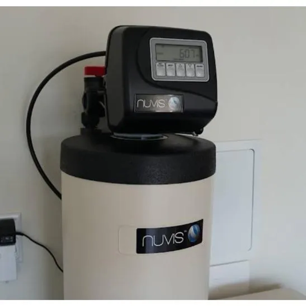Close-up of a Nuvis water conditioner digital control valve showing the LCD interface and buttons.