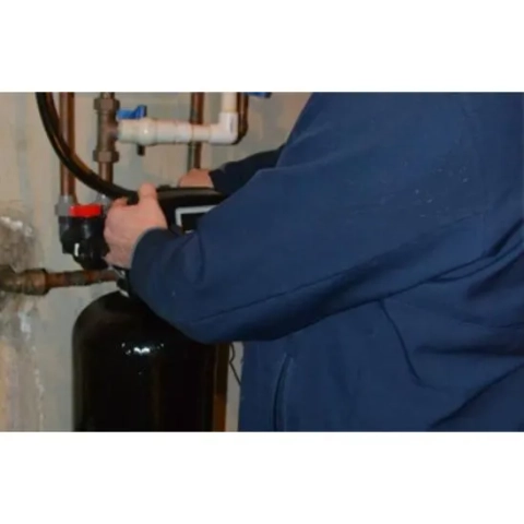 Paul Henderson Plumbing technician installs a new water softening unit in a home basement.