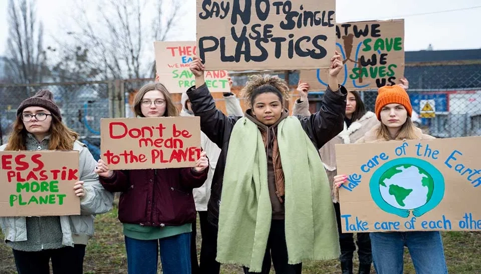 Young activists protest plastic pollution, holding signs promoting environmental care and planet protection.