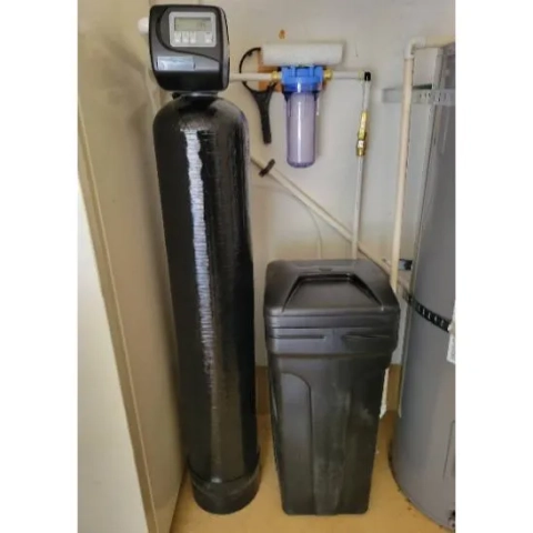 Black fiberglass water softener tank with electronic control valve and separate whole house water filter.