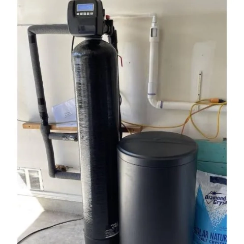 Professional installation of a black Safeguard water softener tank in a residential garage.