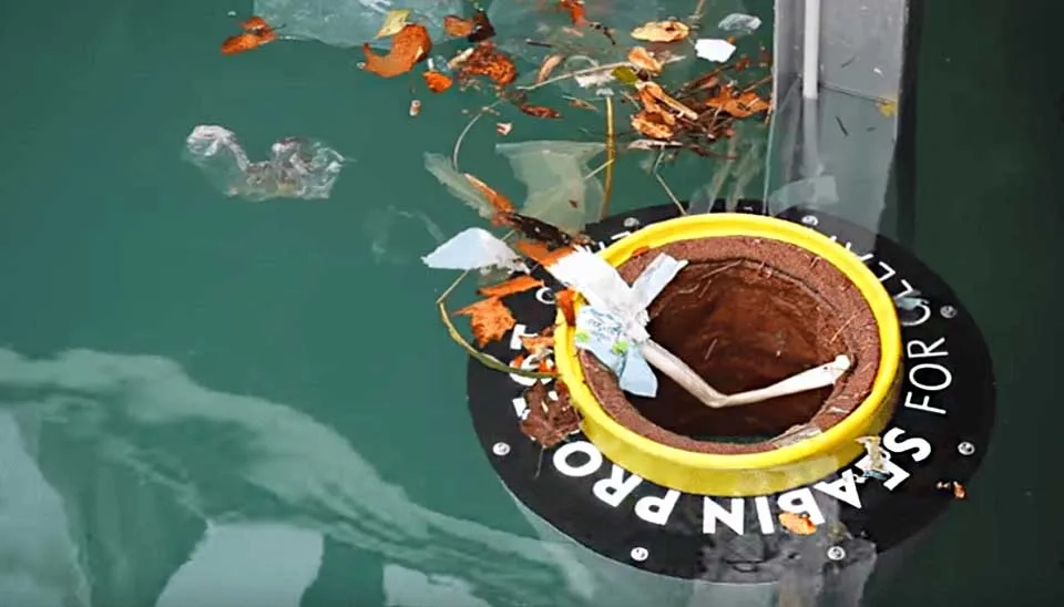 Image of a Sea Bin. Collects small floating trash, demonstrated in calm dockside water environment.