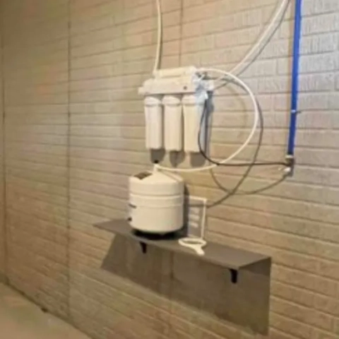 Home water purification setup: multi-stage RO filter system mounted above a white pressurized storage tank