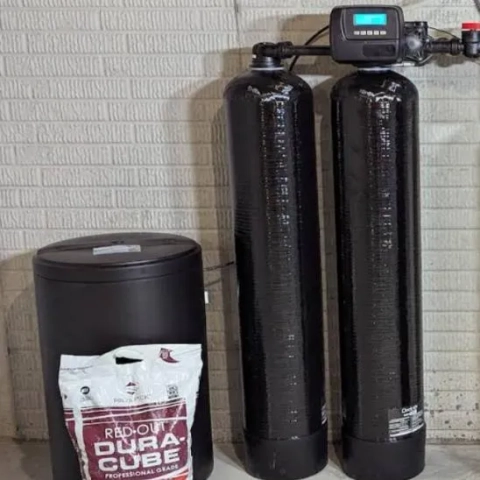 The Softener Guy LLC twin-tank water softener and brine tank next to Red-Out Dura-Cube salt in a residential basement.