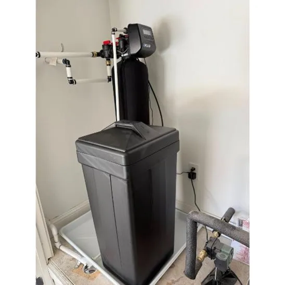 The Water Guy LLC water softener installed indoors with a black resin tank and square brine tank.