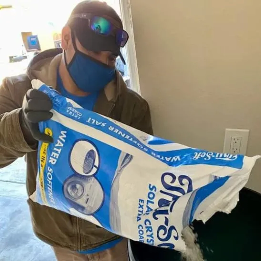 Technician adding Tru-Soft Solar Crystals Extra Coarse salt into residential water softener