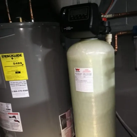 Professional home water conditioning tank equipped with an electronic control head valve to neutralize scaling calcium minerals, expertly installed by Warner Service