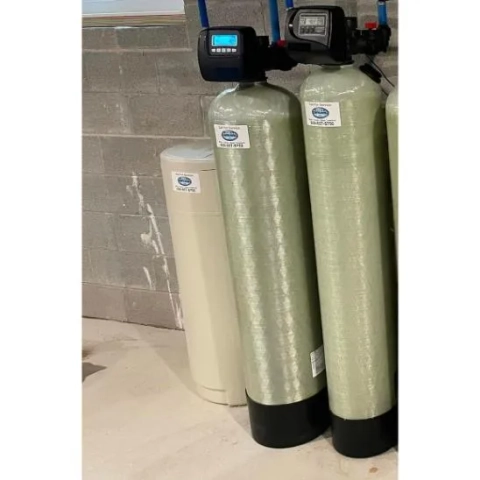 Water Central water conditioning system showing two mineral tanks and a salt tank against a cement wall.