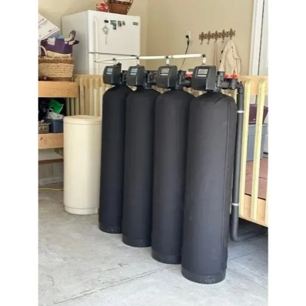 Water Central quadruple water treatment system with black insulated tanks and a large brine tank nearby.