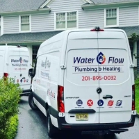 Back view of a Water Flow Plumbing and Heating van showing company logo and service icons.