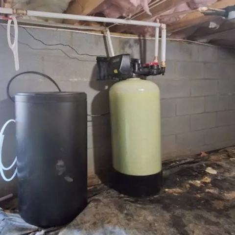 Residential water softener system with brine tank and fiberglass mineral tank in a basement.