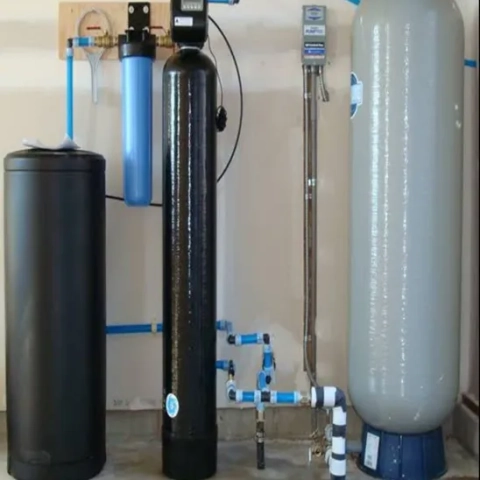 Mike Hensley water softener system setup with a gray pressure tank and blue sediment water filter.