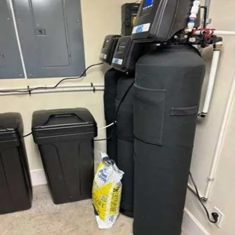 Dual tank water softener system by Water Purification Consultants, Inc. in a utility room.