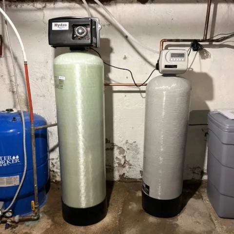 Dual-tank water treatment system with a Hydro-branded control head installed in a basement.