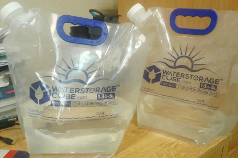 Two WaterStorageCube Collapsible Water Container Bags are filled with water.