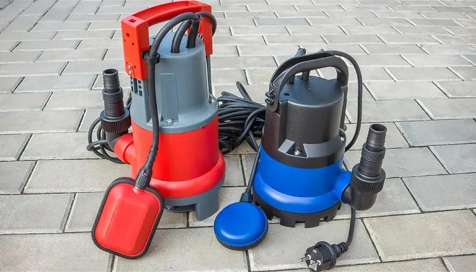Comparison of two submersible pumps with float switches on a paved surface showing different sizes.