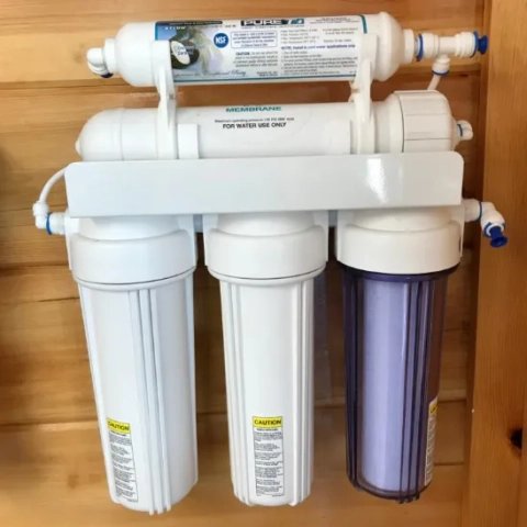 Installed residential reverse osmosis (RO) water purification system on a wooden wall.