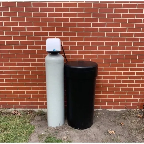 Residential water softener system featuring a white resin tank and black brine tank outdoors