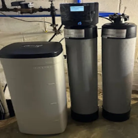 Residential dual-tank water softener and filter system with large gray Clack-style brine tank.