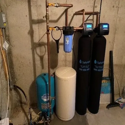 SafeWell dual-tank water filtration system with digital meters, blue pre-filter, and brine tank.