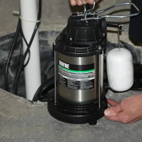 Hands installing a Wayne 3/4 HP stainless steel sump pump with a vertical float for best performance.